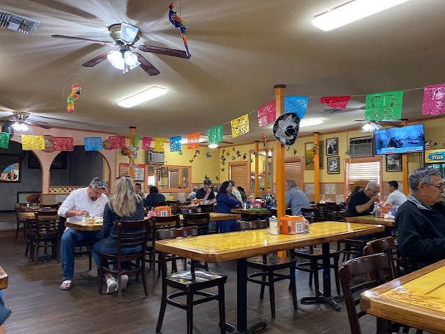 Long wooden tables under papel picado in the dining room